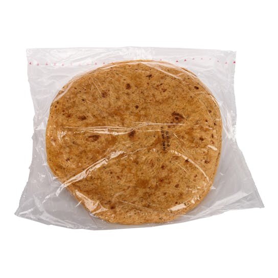 A stack of round, brown tortillas is sealed inside a transparent plastic bag, placed against a white background.