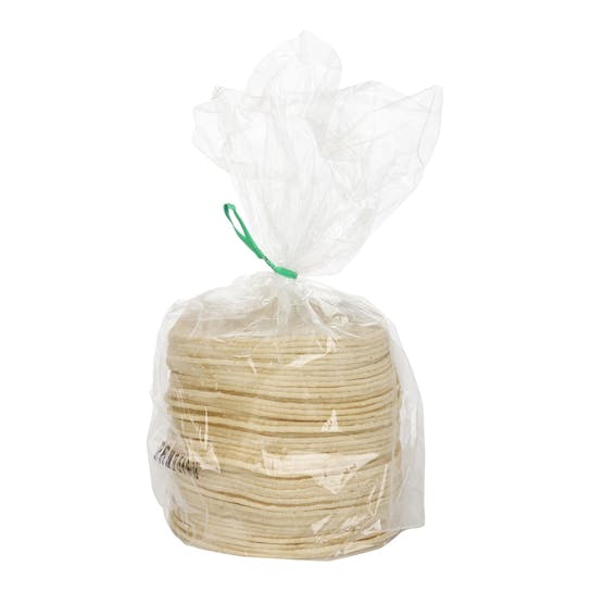 A stack of corn tortillas wrapped in a clear plastic bag, tied at the top with a green twist tie, against a white background.