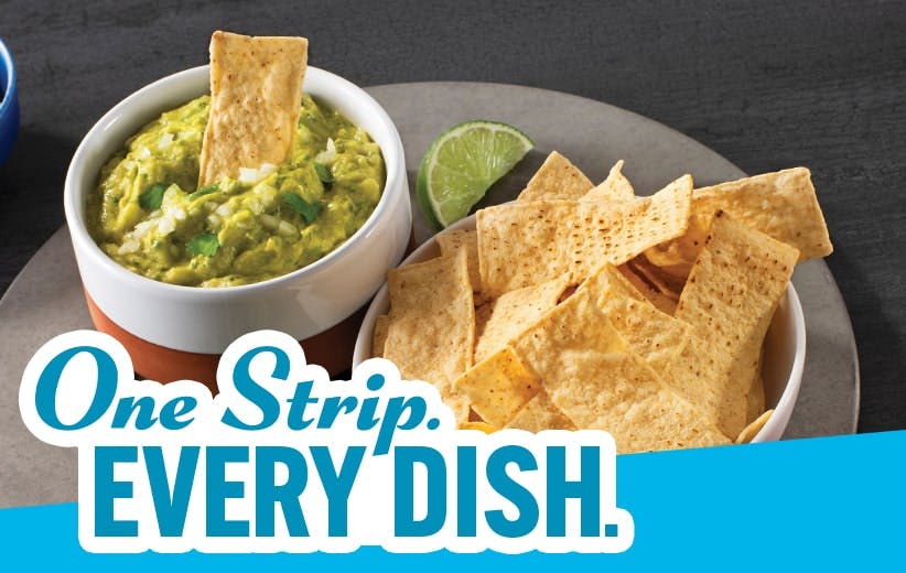 A bowl of guacamole with tortilla chips, a lime wedge, and a bowl of plain tortilla chips are shown on a dark surface. Text across the bottom reads, One Strip. EVERY DISH.